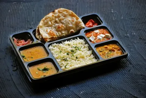 Packed meal tray with rotis, rice, dal, paneer curry, sabzi and salad